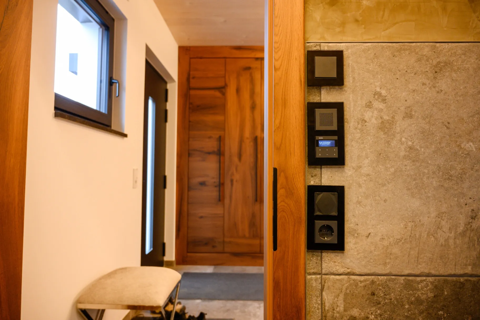 Gira Smart-Home-Bedienelemente an einer Steinwand im Eingangsbereich
