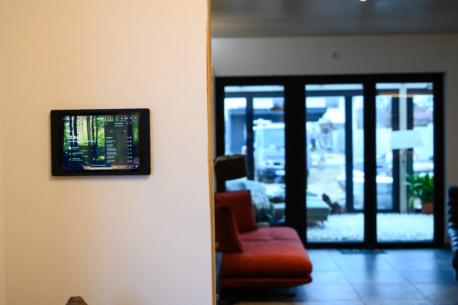 Smart-Home-Bedienpanel an der Wand mit Blick in modernen Wohnraum